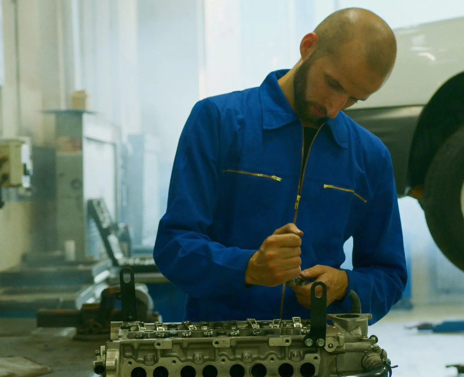 Mecánico trabajando sobre la culata de un motor en el banco del taller