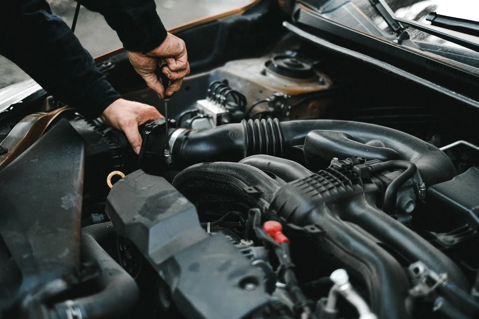Mecánico ajustando una abrazadera en el motor de un carro